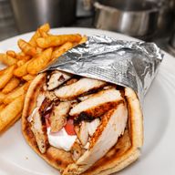 Chicken gyro pita with tomato, onion and sauce, wrapped in foil, with a side of fries