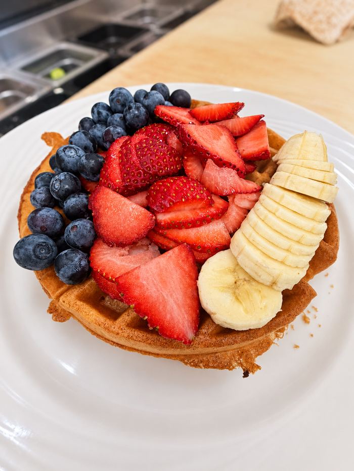 Waffle topped with fresh strawberries, blueberries and sliced banana